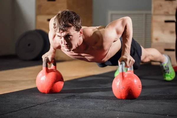 Fiatal, erős férfi csinál fekvőtámaszokat a kettlebell — Stock Fotó