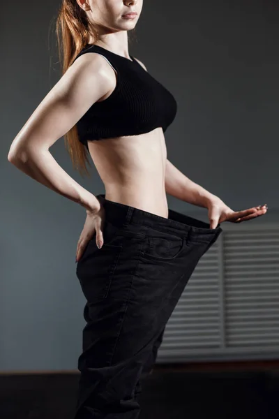 Slim Donna con corpo sottile sano, mostrando i suoi vecchi jeans dopo una dieta di successo . — Foto Stock