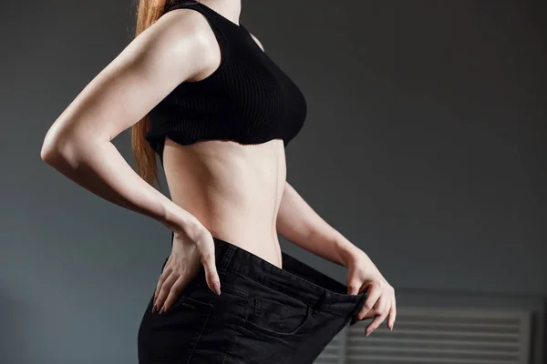 Тонка жінка зі здоровим тонким тілом, показуючи свої старі джинси після успішної дієти . — стокове фото