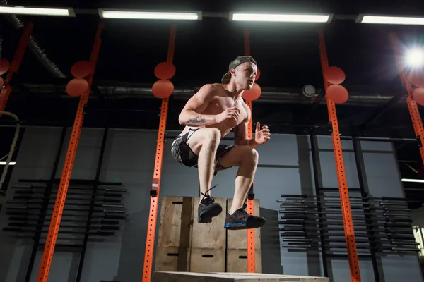 Caja de atleta masculino saltando en el gimnasio de cross fit. El hombre en forma está realizando saltos de caja — Foto de Stock
