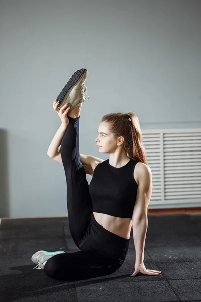 Όμορφη λεπτή μελαχρινή κάνει κάποιες ασκήσεις τεντώματος σε ένα γυμναστήριο — Φωτογραφία Αρχείου