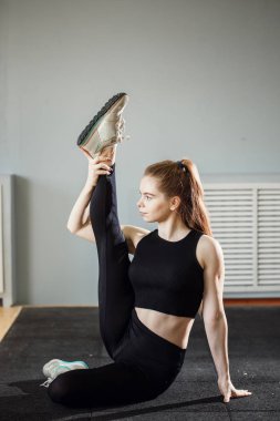 Güzel ince esmer, spor salonunda esneme egzersizleri yapıyor.