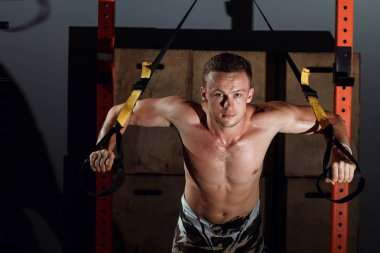 Neşeli genç atlet spor salonunda trx egzersiz yaparak