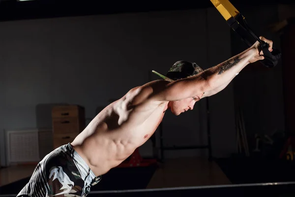 Grande treino TRX. Comprimento total de jovem em sportswear exercitando-se no ginásio — Fotografia de Stock