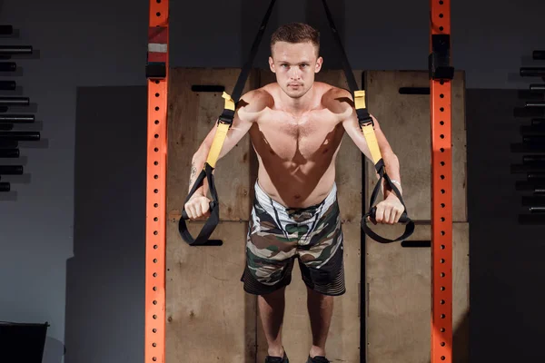 Joven atleta alegre haciendo ejercicio trx en el gimnasio — Foto de Stock