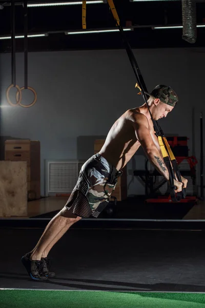 Hombres haciendo flexiones brazos de entrenamiento con correas de fitness trx en el gimnasio —  Fotos de Stock