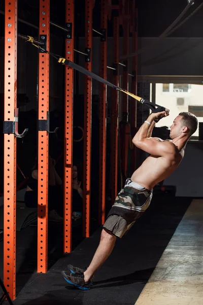 Férfiak során push ups képzés fegyver az edzőteremben trx fitness pántokkal — Stock Fotó