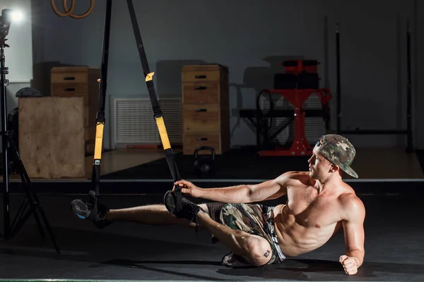 Usando bandas TRX, haciendo flexiones y rotaciones del torso con las piernas suspendidas . — Foto de Stock