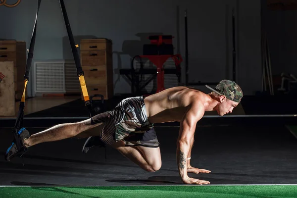 Macho y macho atlético haciendo ejercicios de correas trx en un club de gimnasia . — Foto de Stock