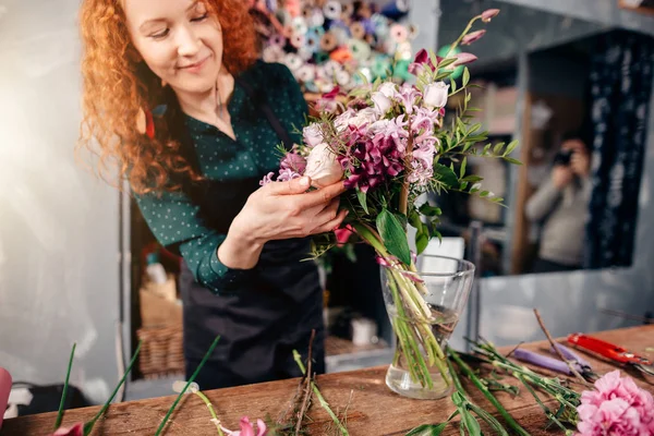 Female putting winsome flowers in vase in florists shop — Stock Photo, Image