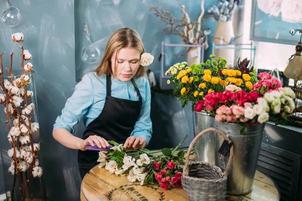 Blond kvinna skära bad blommor på blomstermarknaden — Stockfoto