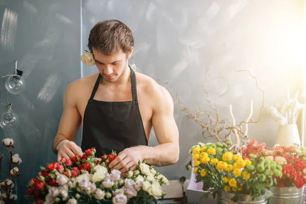 Caucasian man with rose behind his ear working with flowers at flower market