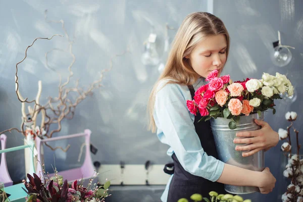 Девушка с длинными светлыми волосами обнимает и нюхает белые и розовые розы — стоковое фото