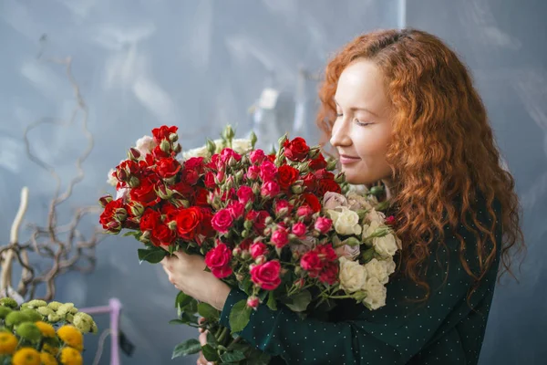 Chica con la cara de rosa cerrando los ojos y ordenando el olor de las rosas — Foto de Stock