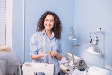 mutlu terzi makas ve kumaş odasında duruyor
