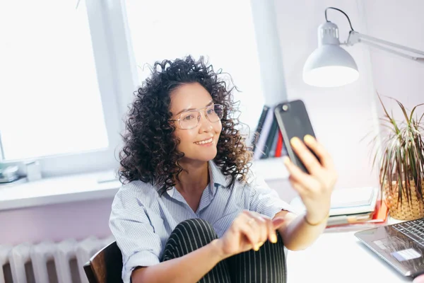 Cropped image of young female taking picture of herself on the chair in room — Stock Photo, Image