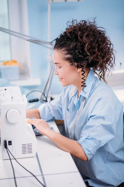 Sede ver foto de costurera trabajadora haciendo clothers con máquina de coser — Foto de Stock