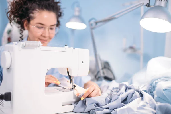 Foto vista lateral da máquina de costura e costureira no processo de trabalho — Fotografia de Stock