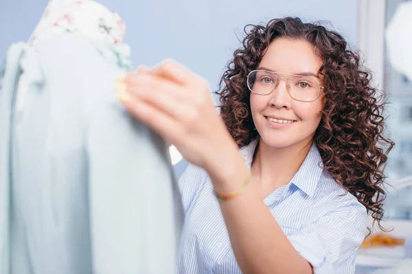 Dressmaker in blue blouse standing behind tailors dummy — Stock Photo, Image