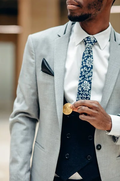 アフリカ人は、スーツのポケットから bitcoin を選択します。男はポケットに bitcoin を置く — ストック写真