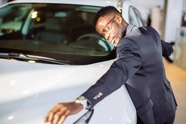 Schöner schwarzer Mann umarmt sein neues Auto und lächelt — Stockfoto