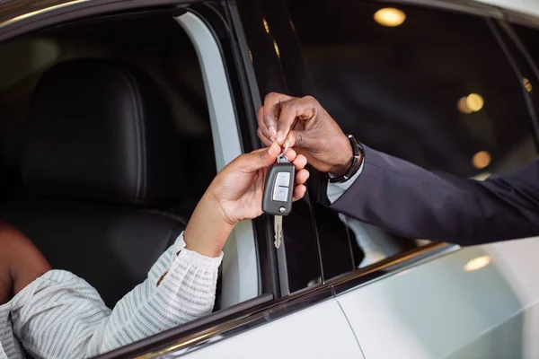 Situação de vendas na concessionária de automóveis, jovem casal africano recebe a chave para o carro novo — Fotografia de Stock