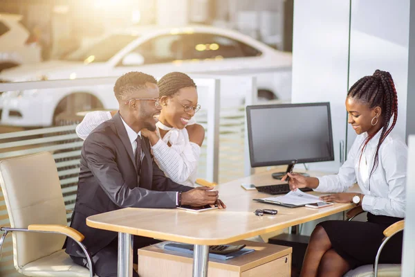 Feliz casal africano com revendedor de compra de carro em auto show ou salão Fotos De Bancos De Imagens