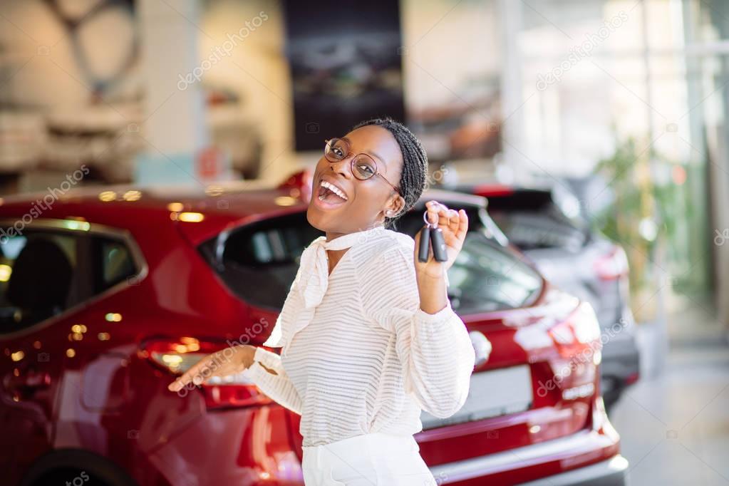 african woman with her new car showing key
