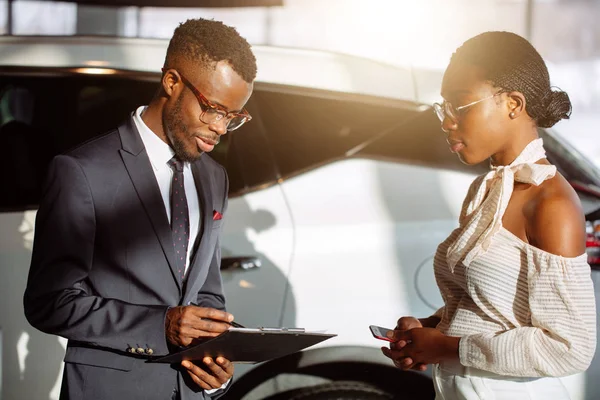 Carro revendedor mostrando veículo para mulher negra — Fotografia de Stock