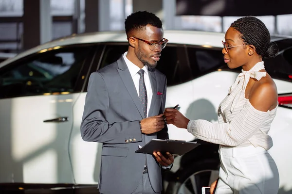 Car dealer showing vehicle to black woman — Stock Photo, Image