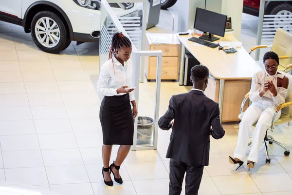 汽车推销员站立在经销商告诉关于汽车的特征对顾客 — 图库照片