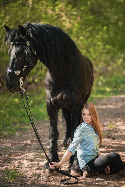 Mujer guapa sentada en el suelo con caballo marrón cerca de ella . — Foto de Stock