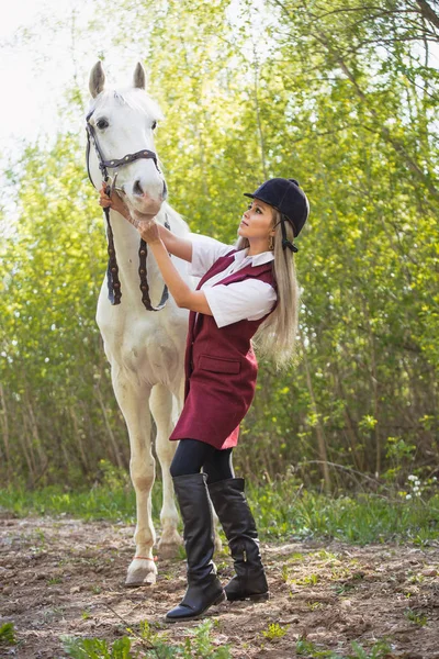 Krásná brunetka s dlouhými vlasy pózuje s červeným koněm v lese — Stock fotografie