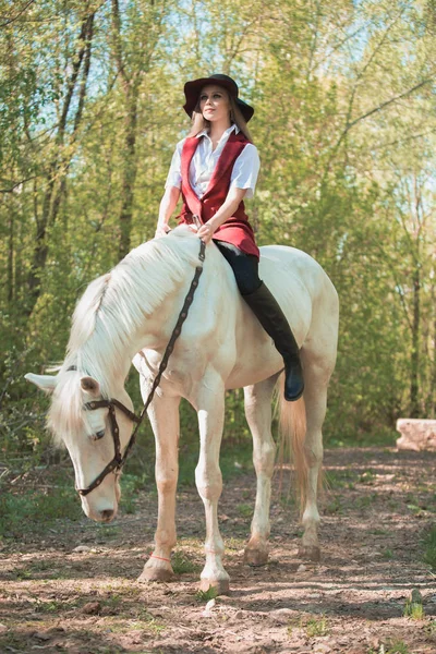 Brunette vrouw rijden dark horse in zomer groen vorst. — Stockfoto