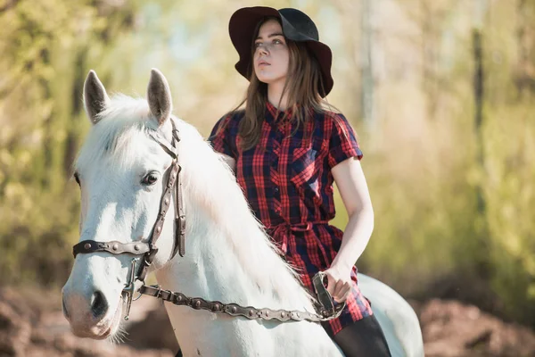 Brunette woman riding dark horse at summer green forest. — Stock Photo, Image