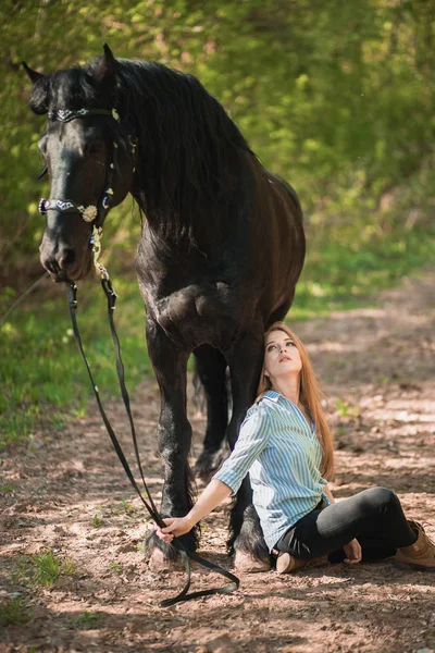 英俊的女人坐在她附近的棕色马地面. — 图库照片