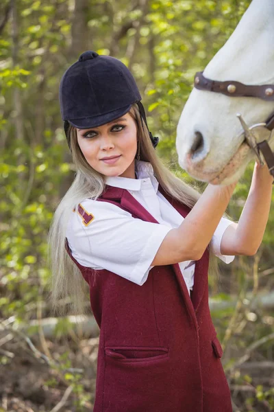 Schöne brünette Mädchen mit langen Haaren posiert mit einem roten Pferd im Wald — Stockfoto