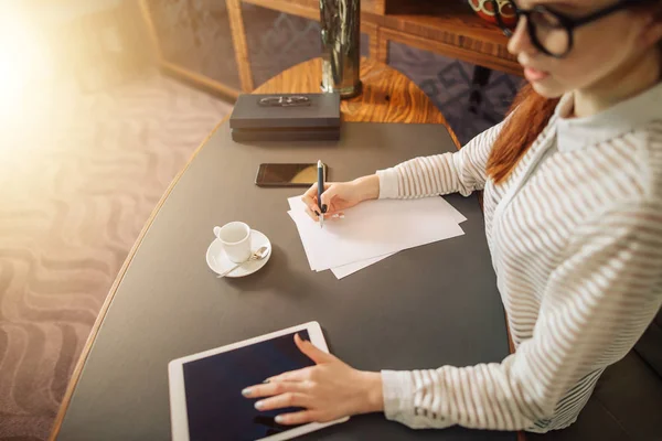 Woman writing on paper with digital tablet computer in office room — Stock Photo, Image