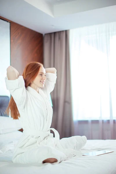 Rödhårig kvinna stretching i sängen efter uppvaknandet — Stockfoto