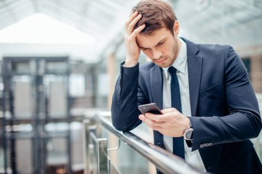 Endişeli genç işadamı Oku metin üstünde hareket eden telefon