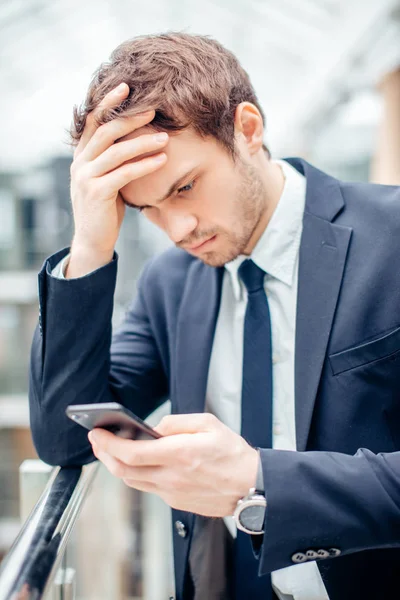 Aggódik fiatal üzletember olvasható szöveg-ra mozgatható telefon — Stock Fotó