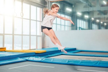 Girl jumping high in striped tights on trampoline. clipart