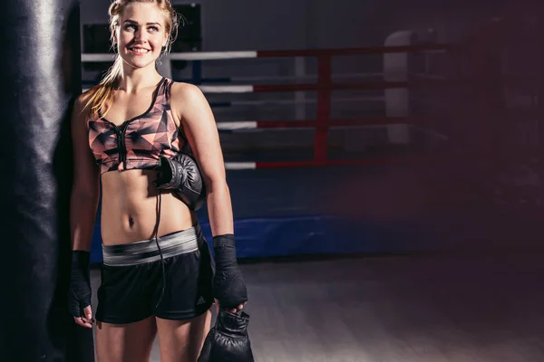 Donna pugile appoggiato in avanti per riposare su un enorme sacco da boxe — Foto Stock