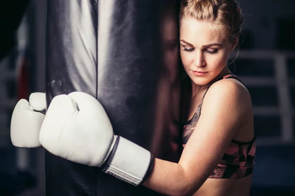 Savaşçı kız boks torbası ile spor salonunda. Uzun saçlı kadın fitness modeli — Stok fotoğraf