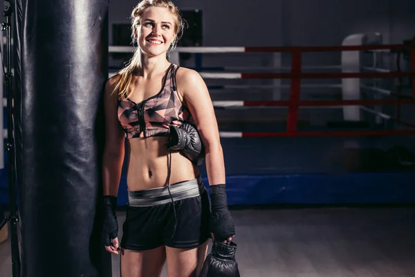 Büyük bir kum torbası üzerinde dinlenmek için öne eğilerek kadın boksör — Stok fotoğraf