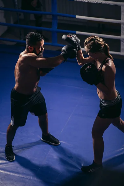 Entrenamiento de la chica de boxeo en guantes de boxeo en poder de un boxeador maestro —  Fotos de Stock