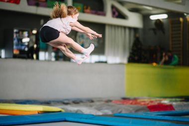 Kız yüksek şeritli tayt içinde trambolin üzerinde atlama.