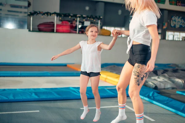 Moeder en dochter springen op de trampoline en split doen — Stockfoto