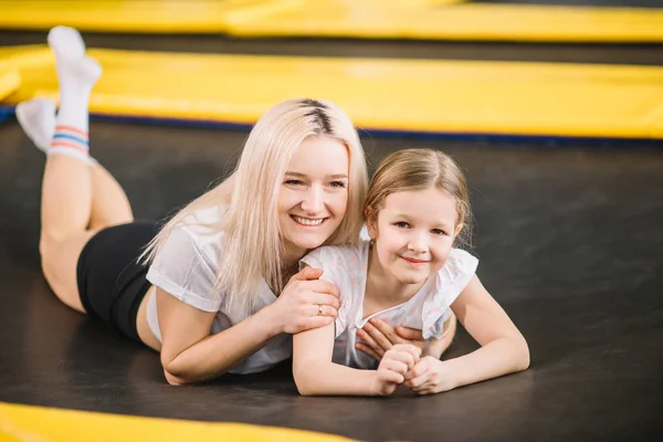 Moeder en meisje spelen in speeltuin en liggend op een trampoline — Stockfoto