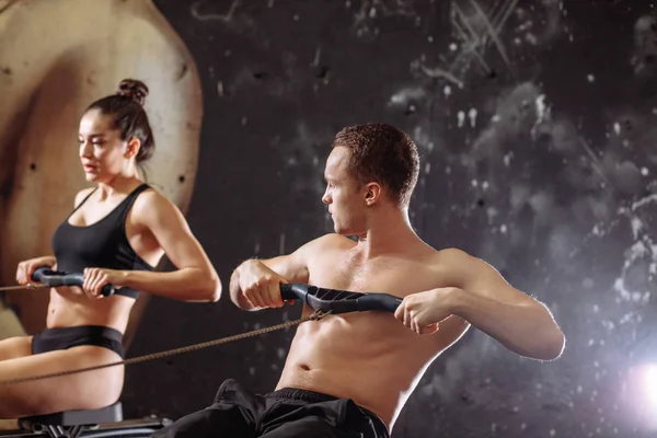 Par gör övningar med roddmaskin — Stockfoto